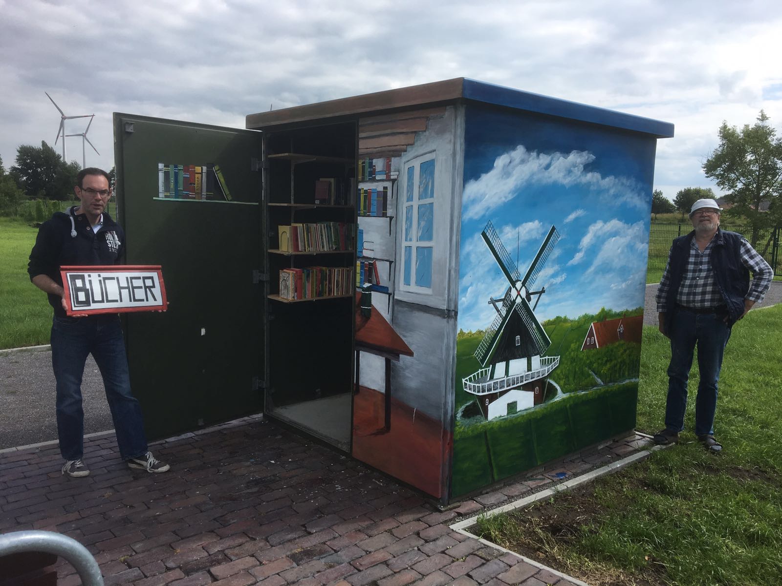 Das Bild zeigt Maler Heinz Holstein und Ortsvorsteher Henning Bernau, vor der neuen Bcherei auf dem umgestalteten Sportplatz. 